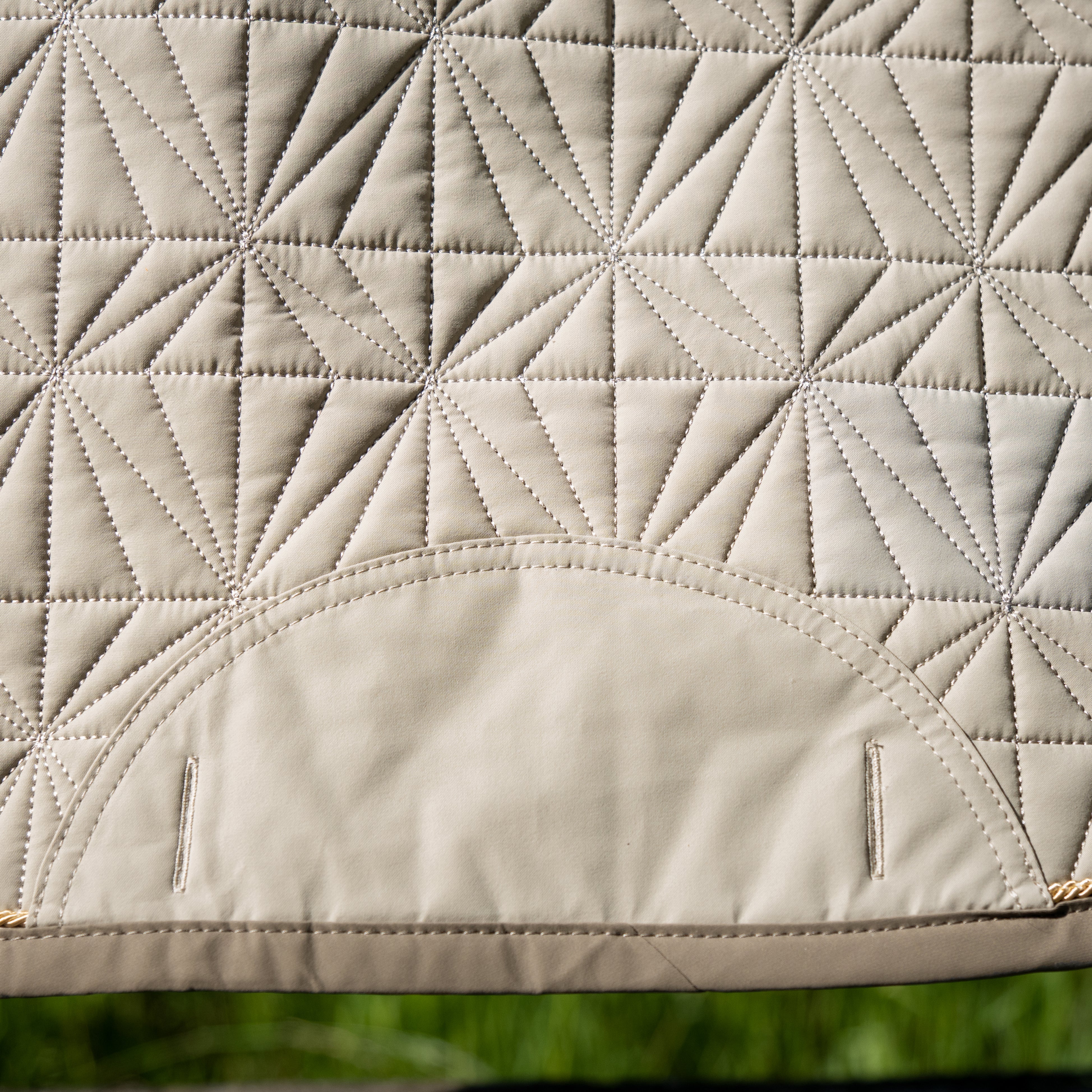 Detailansicht des beigen ROSS KANI Schabracken-Covers mit geometrischem Steppmuster und robusten Gurtschlitzen – elegantes und funktionales Reitzubehör.