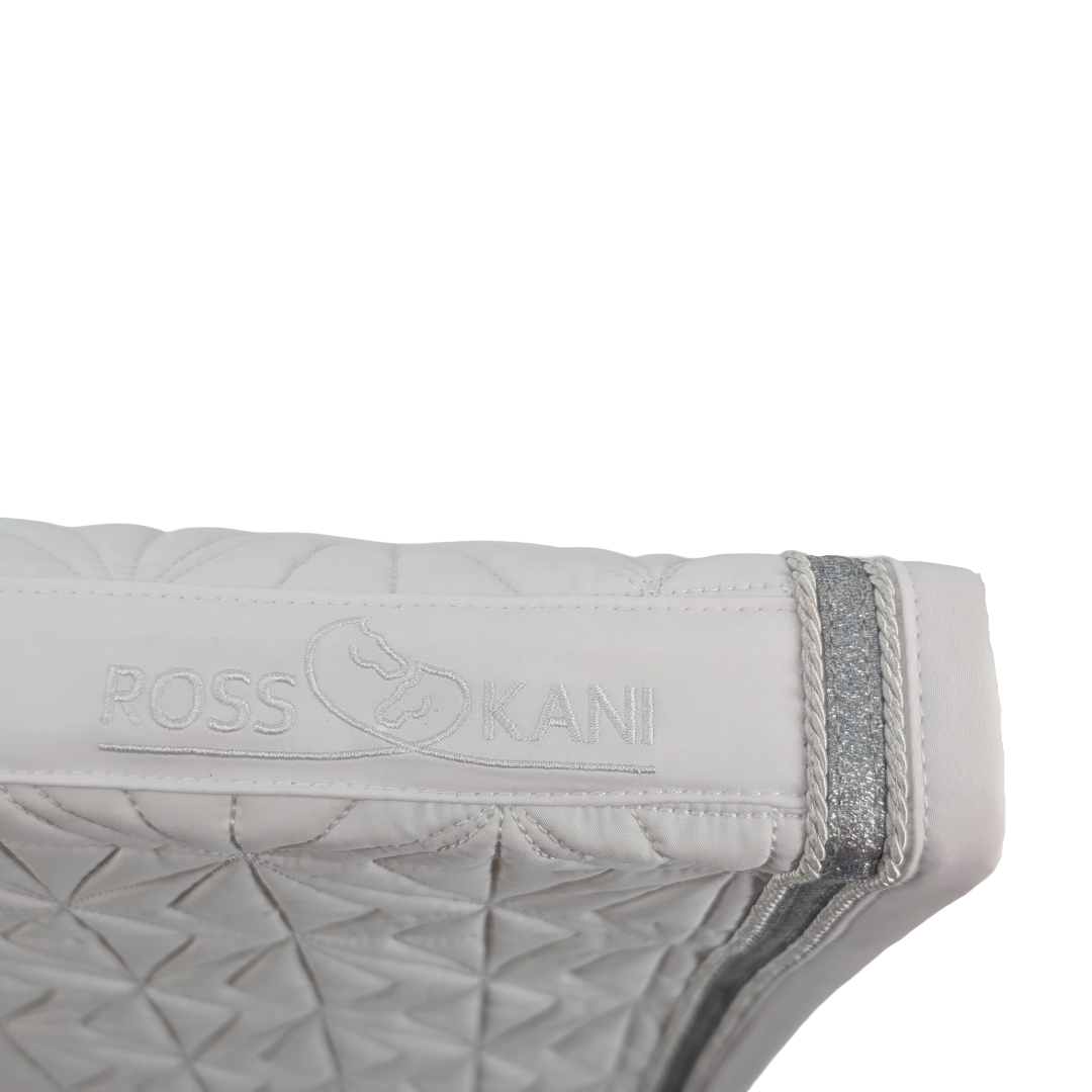 Detailaufnahme des gesteppten ROSS KANI Logos auf dem weißen Schabracken-Cover – hochwertig verarbeitet.