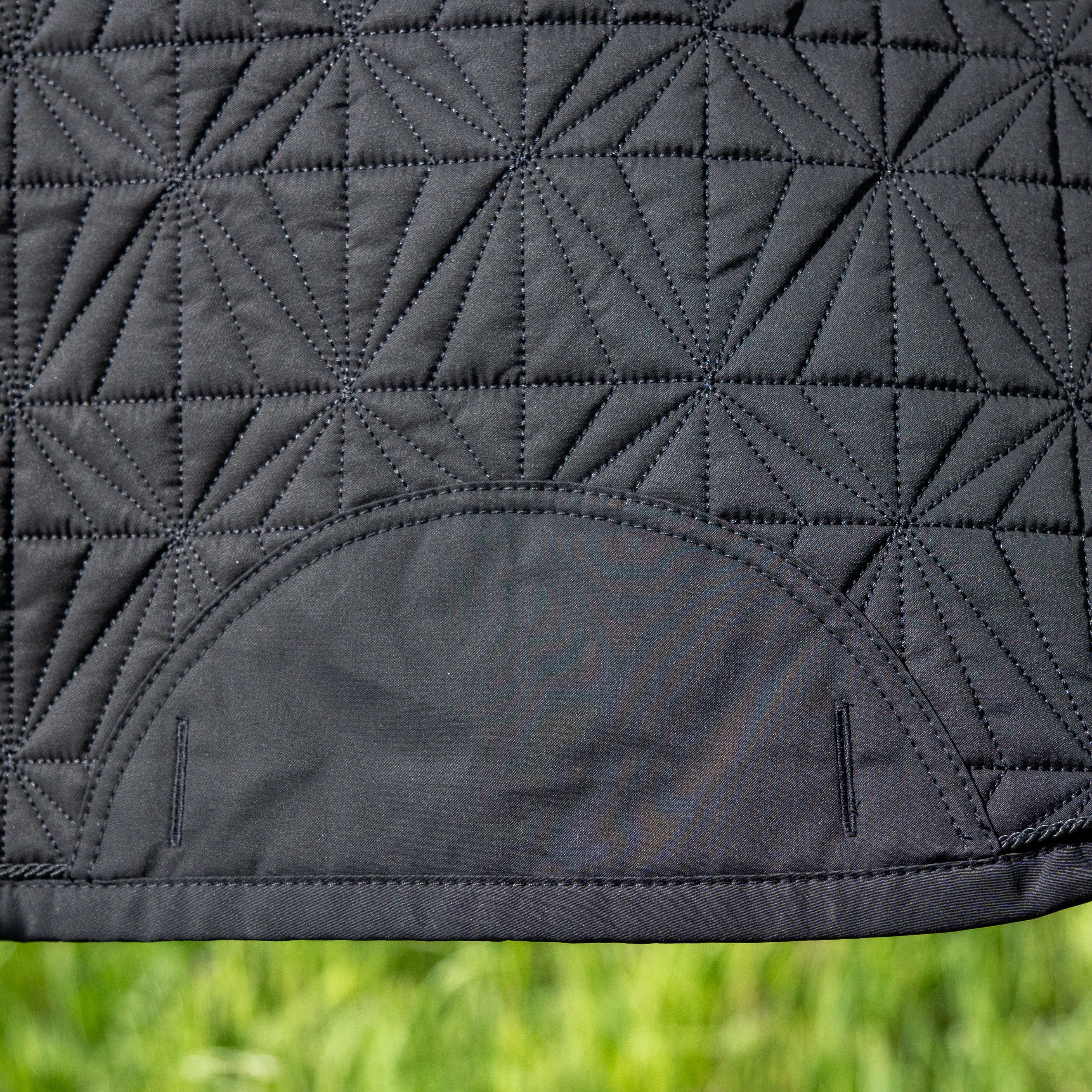 Detailansicht des schwarzen ROSS KANI Schabracken-Covers mit geometrischem Steppmuster und robusten Gurtschlitzen – elegantes und funktionales Reitzubehör.