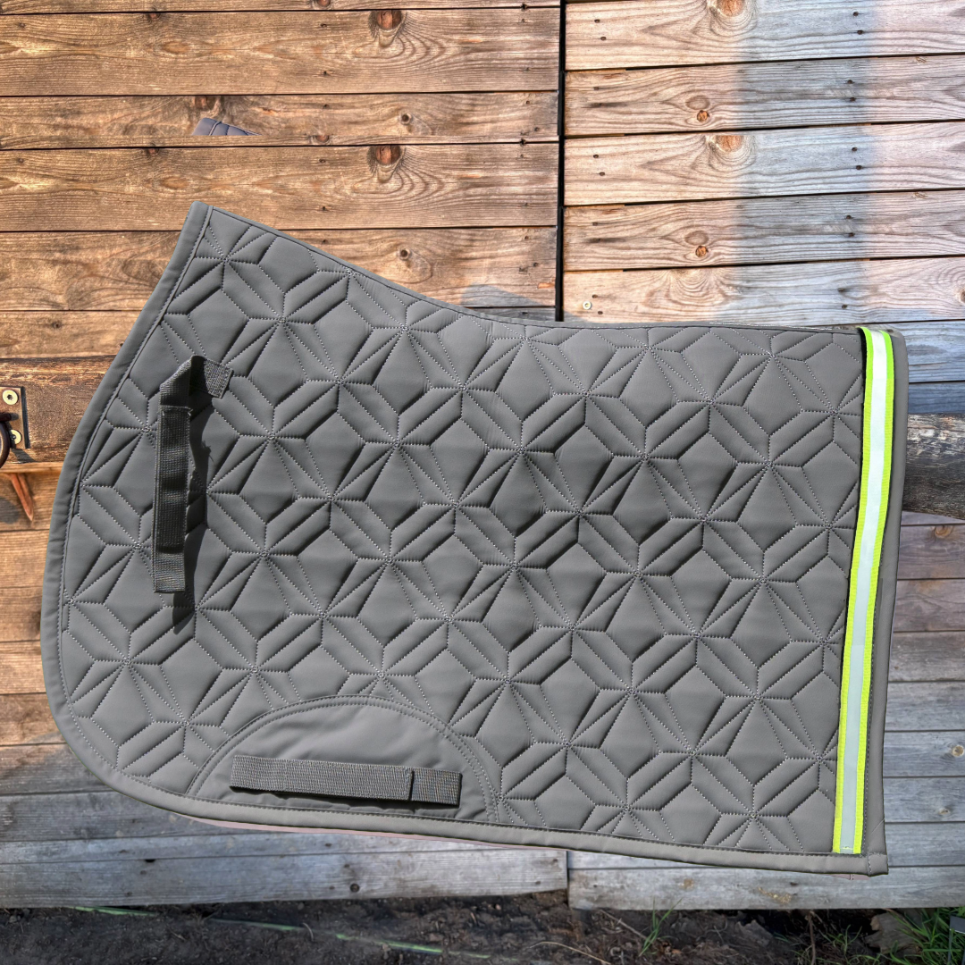 Graue Springschabracke von ROSS KANI vor einer Holzwand mit aufgeklettetem neonfarbenen Klettband mit reflektierendem Streifen.