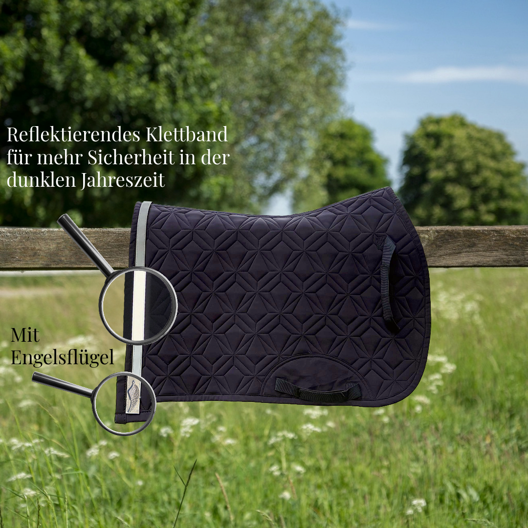 Blau, gesteppte Springschabracke von ROSS KANI hängt über einem Holzzaun auf einer Wiese. Ein reflektierendes Klettband mit Engelflügel-Charm ist am Rand befestigt und wird durch eine Lupe hervorgehoben. Text im Bild weist auf erhöhte Sicherheit in der dunklen Jahreszeit hin.
