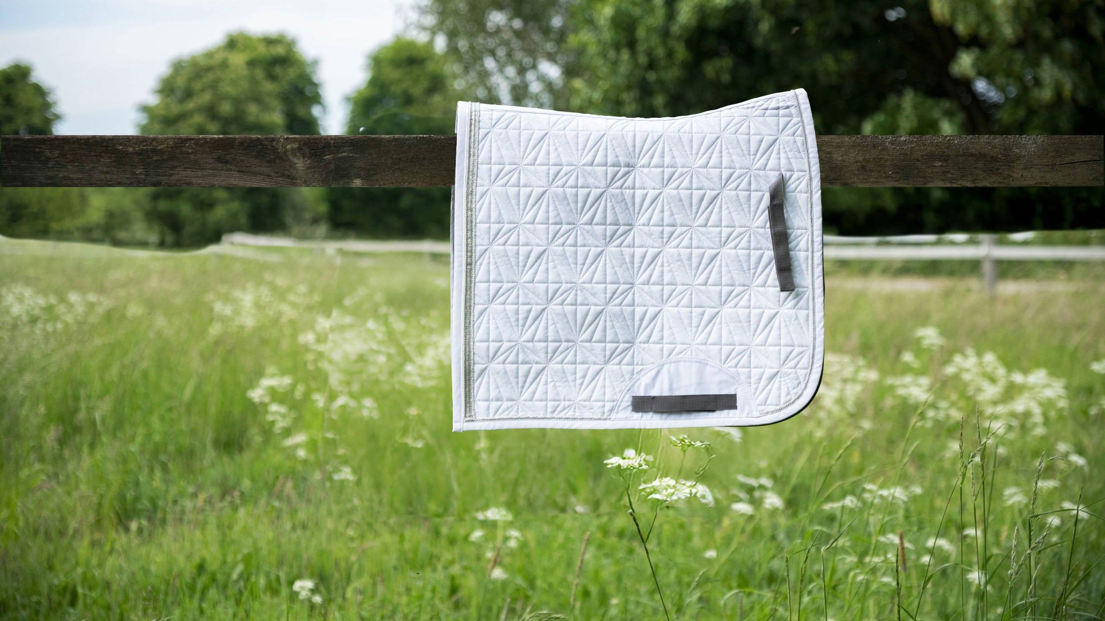 Weißes Dressurschabracken-Cover in Seitenansicht auf grauer Hauptschabracke von ROSS KANI – elegante Steppung und anatomische Passform.