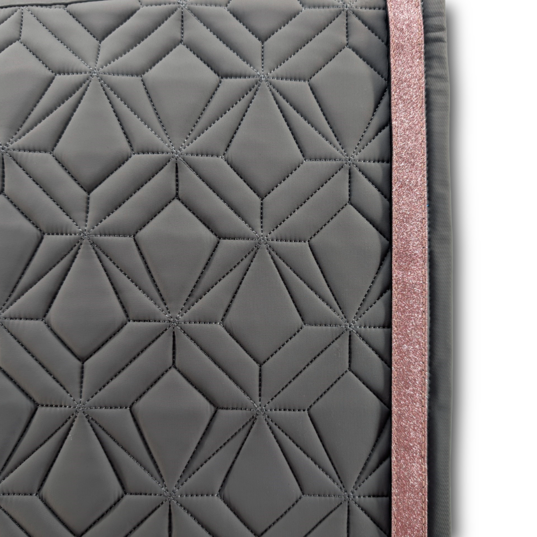 Detailansicht der graufarbenen ROSS KANI Schabracke mit geometrischem Steppmuster und rosa Glitzerband – elegantes Design für stilbewusste Reiterinnen.