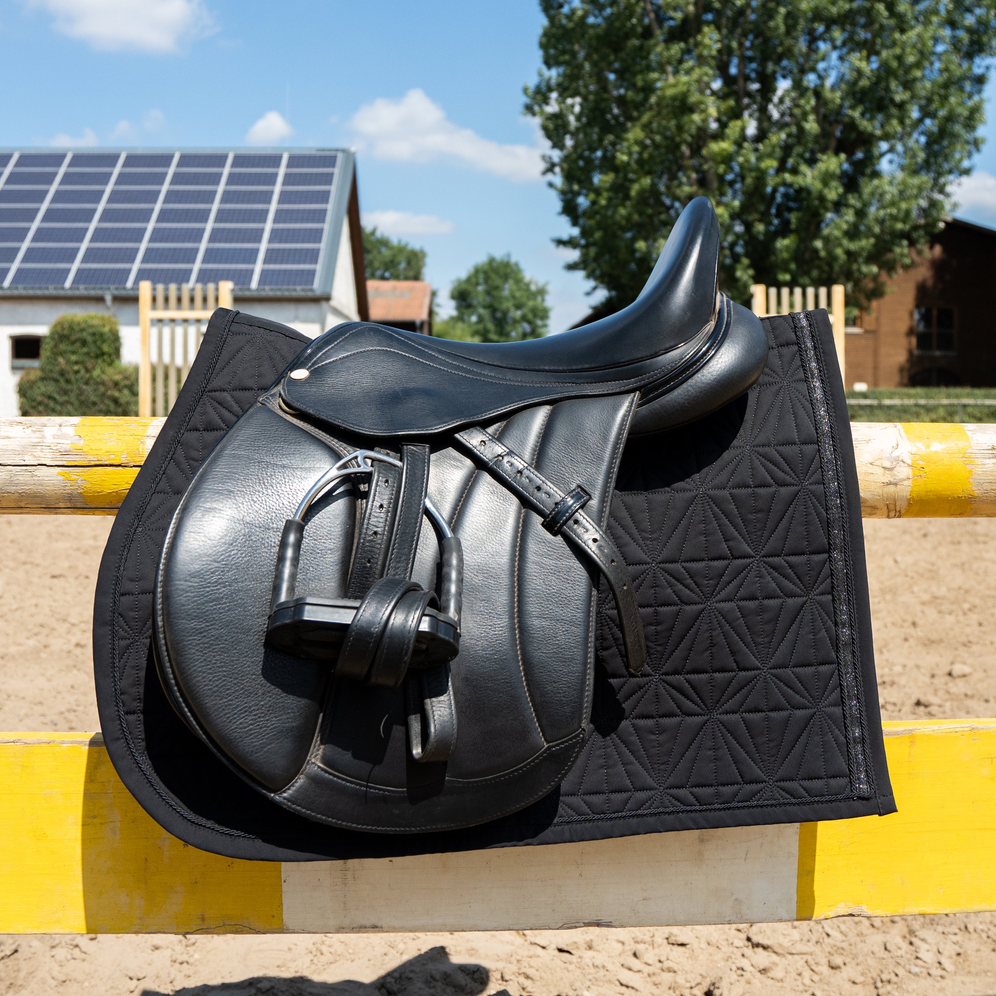 Schwarzes Springschabracken-Cover von ROSS KANI über der Stange auf dem Springplatz - perfekter Sitz für jeden Sprung.