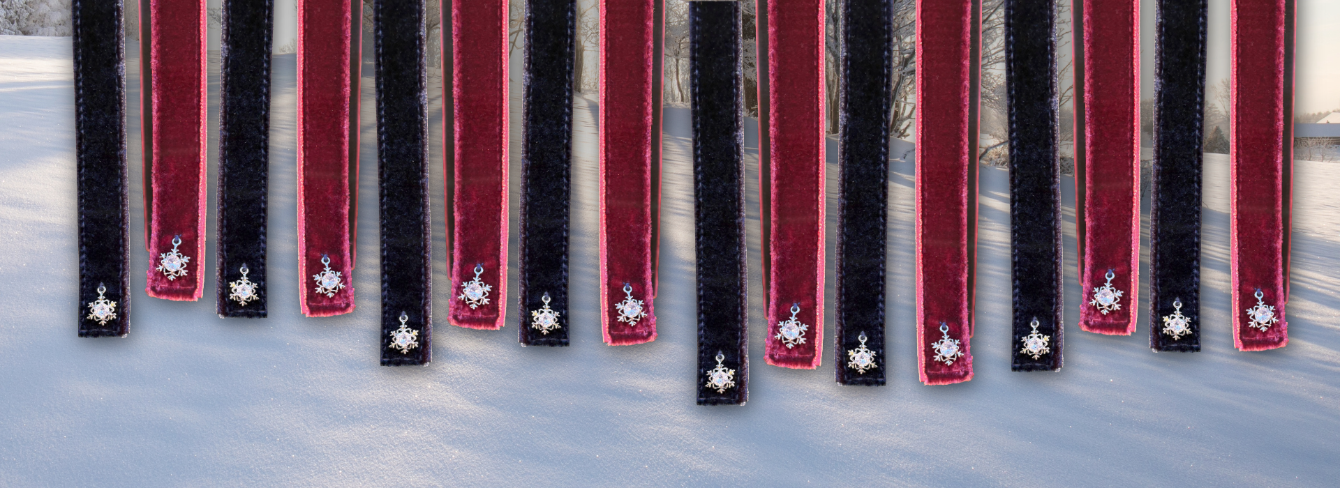 Mehrere blaue und rote winterliche Samtklettbänder mit Schneeflocken-Charm von ROSS KANI vor einer schneebedeckten Winterlandschaft.