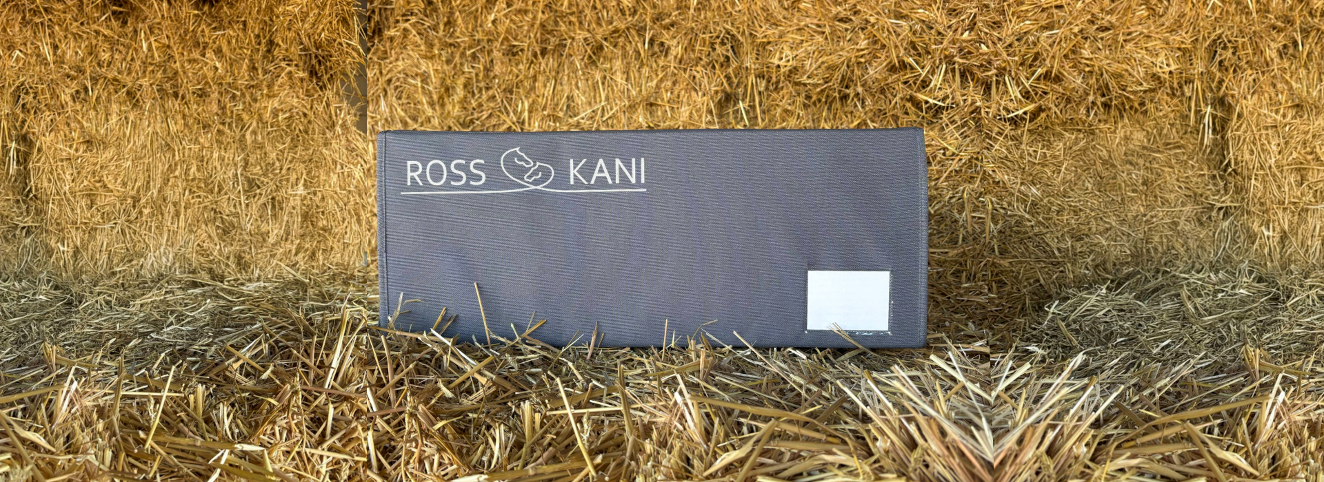 ROSS KANI Aufbewahrungsbox für 5 Schabracken liegt auf einem Strohballen, im Hintergrund ist auch Stroh zu sehen – wasserfestes Polyester mit Sichtfenster und Klettverschluss
