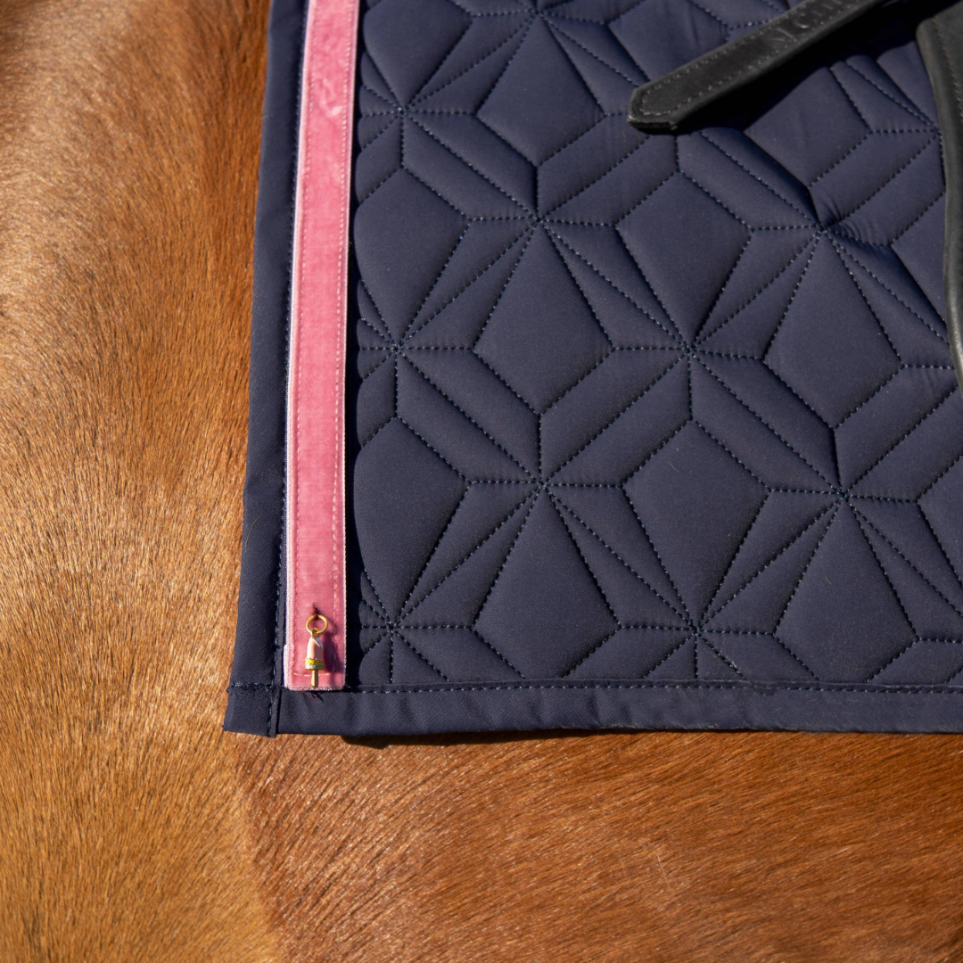 Blaue Schabracke von ROSS KANI mit Frühlingsband rosa und Eis-Charme in Nahaufnahme auf dem Pferd.