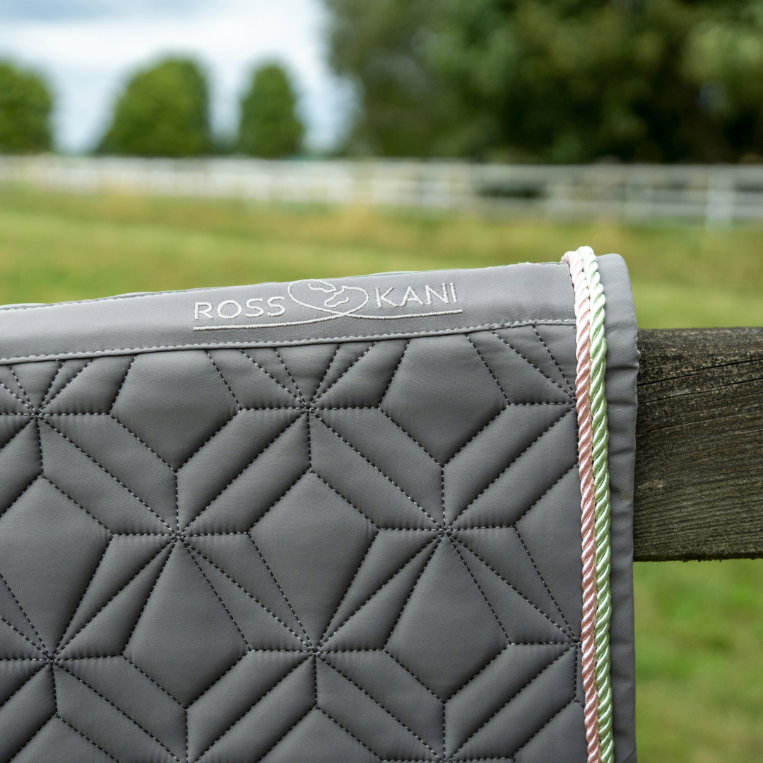 Detailansicht der grauen ROSS KANI Classic Schabracke mit Logo, geometrischer Steppung und rosa-grüner Kordel