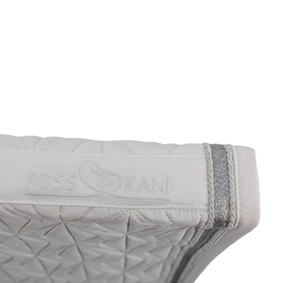 Detailaufnahme des gesteppten ROSS KANI Logos auf dem weißen Schabracken-Cover – hochwertig verarbeitet.