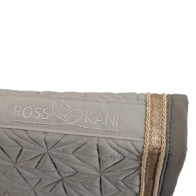 Detailaufnahme des gesteppten ROSS KANI Logos auf dem beigen Schabracken-Cover – goldene Kordel, goldenes Glitzerband.