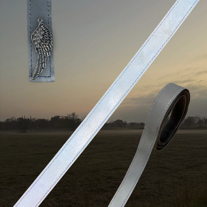 Reflektierende Bänder von ROSS KANI mit Engelflügel-Charm vor einem nebelig dunklem Hintergrund – hochwertiges, strapazierfähiges Klettband zur sicheren Befestigung an Schabracken von ROSS KANI, ideal für die dunkle Jahreszeit.