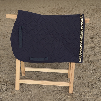 Blaue ROSS KANI Springschabracke auf Holzbock mit gold schimmerndem Leoklettband vor hellem Sandboden
