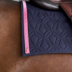 Blaue Hauptschabracke von ROSS KANI liegt auf einem braunen Pferd. Das rosa Samtklettband mit kleinem Anhänger in Eisform ist aufgeklettet. Auf der Schabracke liegt eine brauner Sattel. 
