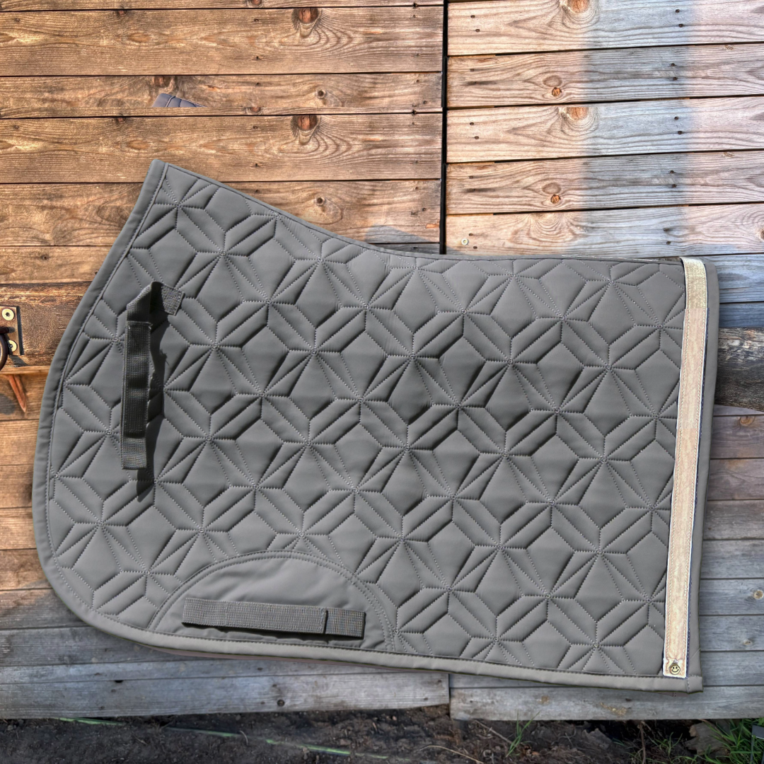 Graue Springschabracke von ROSS KANI mit beigem Frühlingsband und Smiley-Charm vor einer Holzwand.