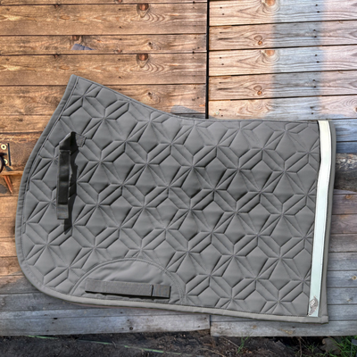 Graue Springschabracke von ROSS KANI vor einer Holzwand mit aufgeklettetem grauem Reflektor-Klettband mit Flügelanhänger.