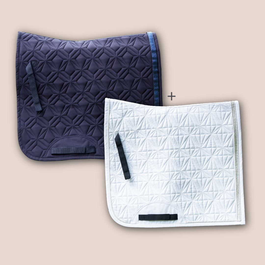 Blaue Dressurschabracke und weißes Dressur-Cover von ROSS KANI vor roséfarbenem Hintergrund mit Diamant- und Rautensteppung.