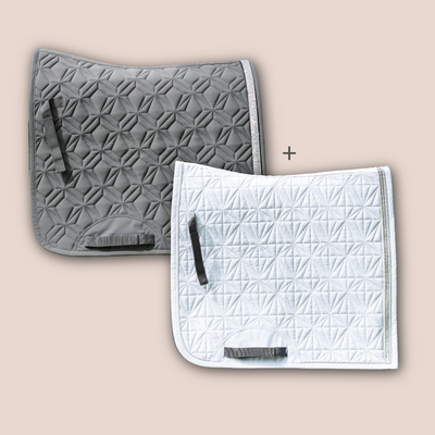 Graue Dressurschabracke und weißes Dressur-Cover von ROSS KANI vor roséfarbenem Hintergrund mit Diamant- und Rautensteppung.