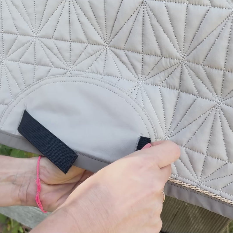 Video: Die blaue Dressur-Hauptschabracke von ROSS KANI hängt über einem Koppelzaun. Das beige Dressur-Cover wird aufgeklettet. Im Hintergrund sieht man ein bisschen Wiese.