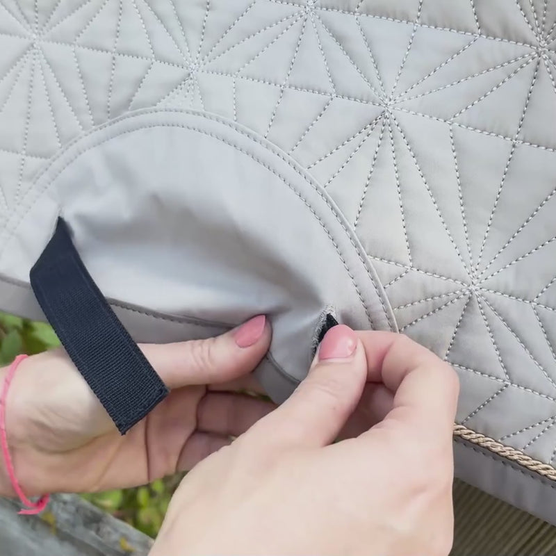 Video: Die blaue Spring-Hauptschabracke von ROSS KANI hängt über einem Koppelzaun. Das beige Spring-Cover wird aufgeklettet. Im Hintergrund sieht man ein bisschen Wiese.
