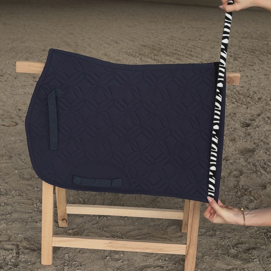 Blaue ROSS KANI Spring-Schabracke auf Holzbock in Reithalle. Zebraklettband wird auf- und abgeklettet