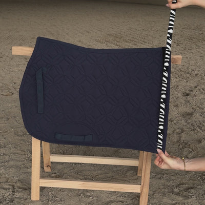 Blaue ROSS KANI Spring-Schabracke auf Holzbock in Reithalle. Zebraklettband wird auf- und abgeklettet