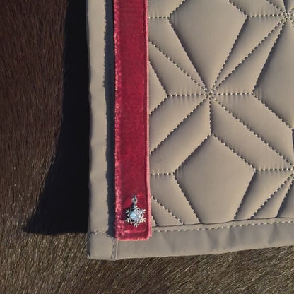 Video: Dunkelrotes Samtband mit Schneeflocken-Charm von ROSS KANI wird auf der grauen Schabracke befestigt – einfache Handhabung.