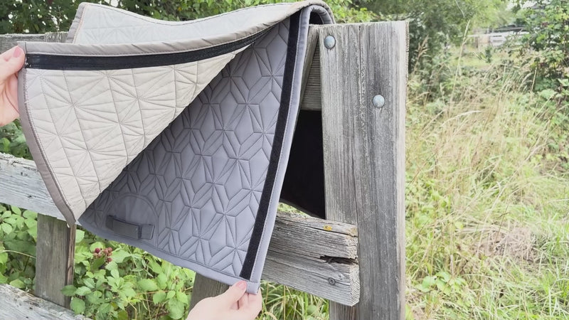 Video: Beiges Spring-Cover von ROSS KANI wird auf der blauen Schabracke befestigt – einfache Handhabung. Die Schabracke hängt über einem Koppelzaun und im Hintergrund sieht man Wiese.